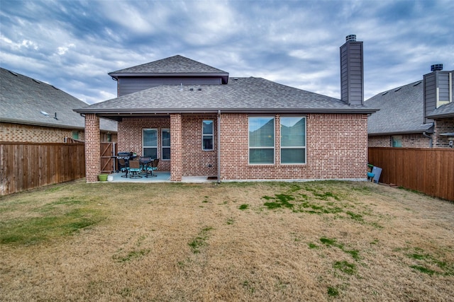 back of house with a patio area and a lawn