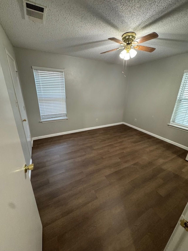 empty room featuring dark wood-type flooring, a textured ceiling, and ceiling fan