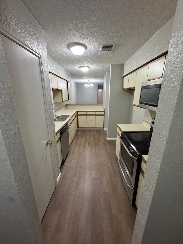 kitchen with sink, hardwood / wood-style floors, appliances with stainless steel finishes, and a textured ceiling