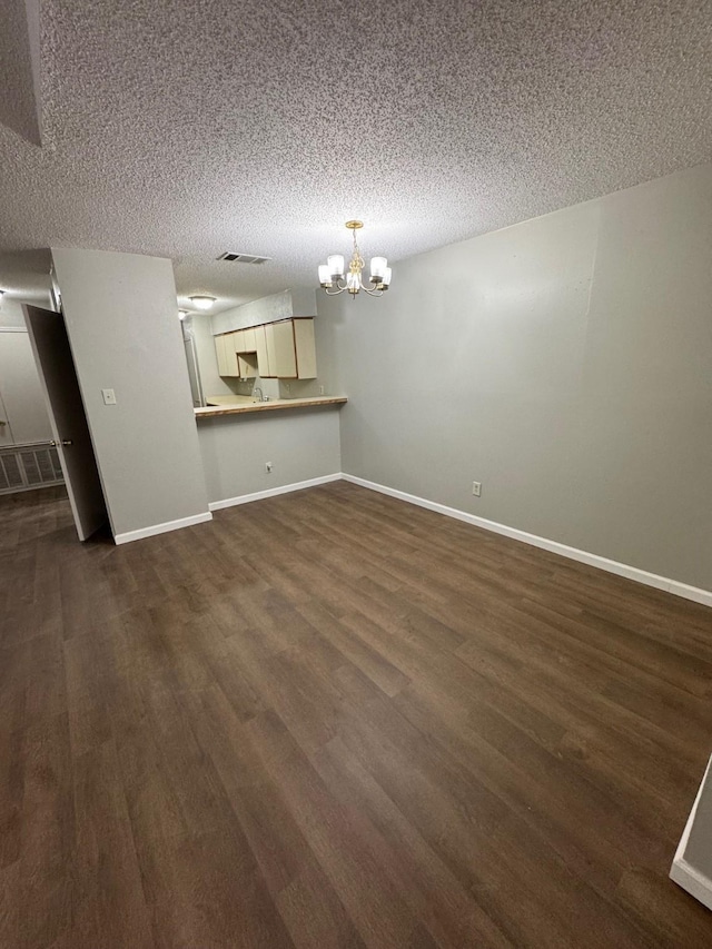 unfurnished living room with a textured ceiling, dark wood-type flooring, and a chandelier