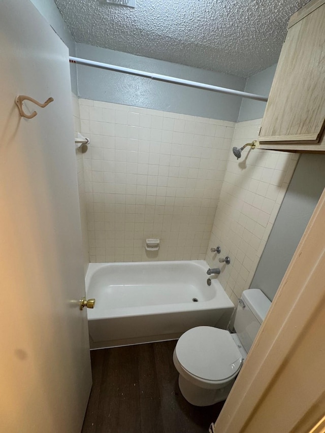 bathroom featuring hardwood / wood-style flooring, tiled shower / bath, a textured ceiling, and toilet