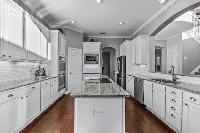 kitchen featuring white cabinets, a center island, stainless steel appliances, sink, and backsplash