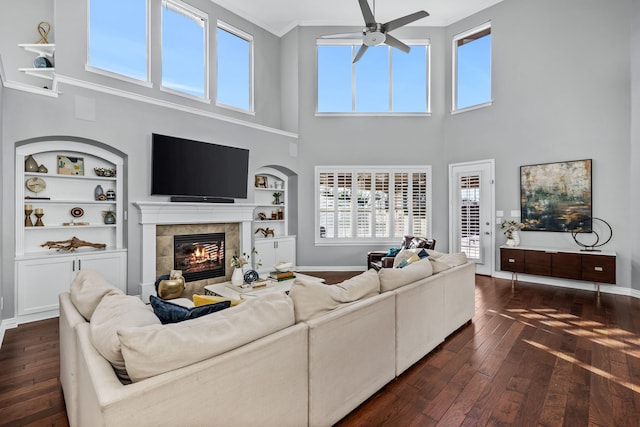 living room with built in features, dark hardwood / wood-style flooring, and a tiled fireplace