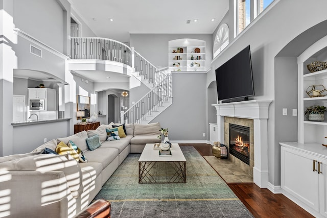 living room with built in shelves, a tile fireplace, dark hardwood / wood-style floors, and a wealth of natural light