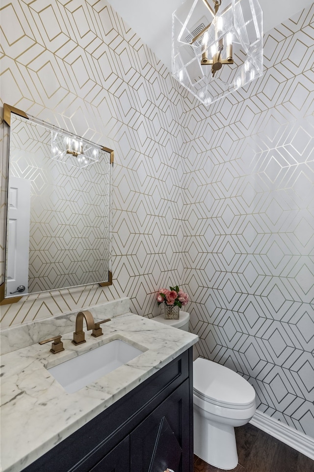 bathroom with a chandelier, toilet, vanity, and tile walls