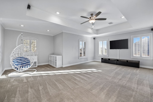 unfurnished room featuring a raised ceiling, ornamental molding, plenty of natural light, and light carpet