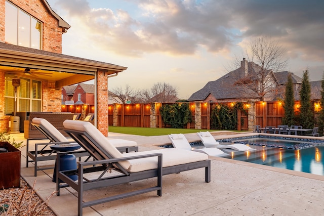 pool at dusk featuring a patio and ceiling fan