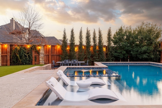 pool at dusk featuring a patio area