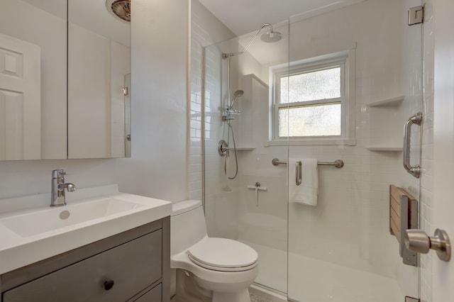 bathroom featuring a shower with door, toilet, and vanity