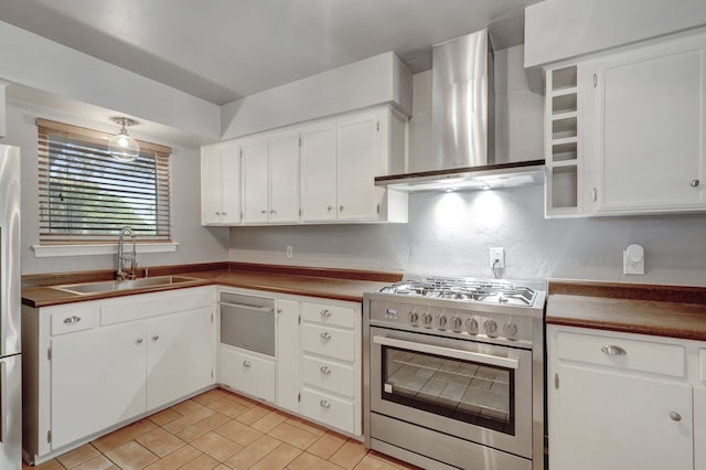 kitchen with wall chimney exhaust hood, white cabinetry, stainless steel appliances, sink, and light tile patterned floors