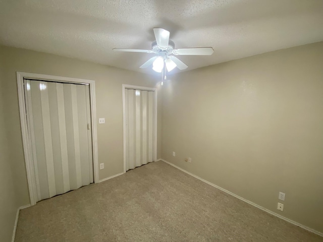 unfurnished bedroom featuring ceiling fan, light colored carpet, and a textured ceiling