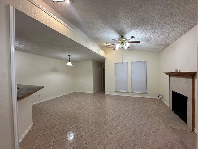 unfurnished living room featuring vaulted ceiling, ceiling fan, light tile patterned floors, a fireplace, and a textured ceiling