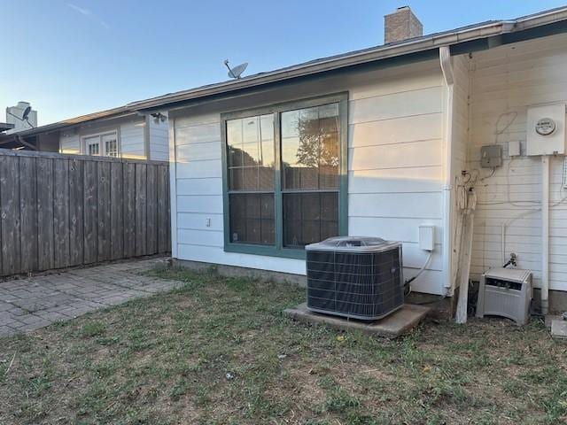 back of house with central AC unit and a lawn