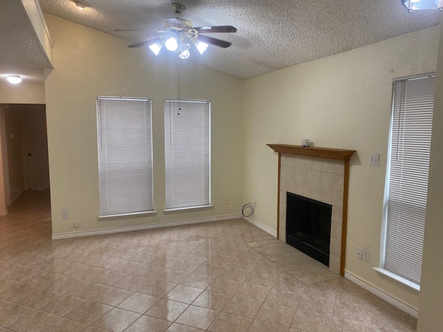 unfurnished living room featuring ceiling fan, a tiled fireplace, a textured ceiling, and light tile patterned flooring