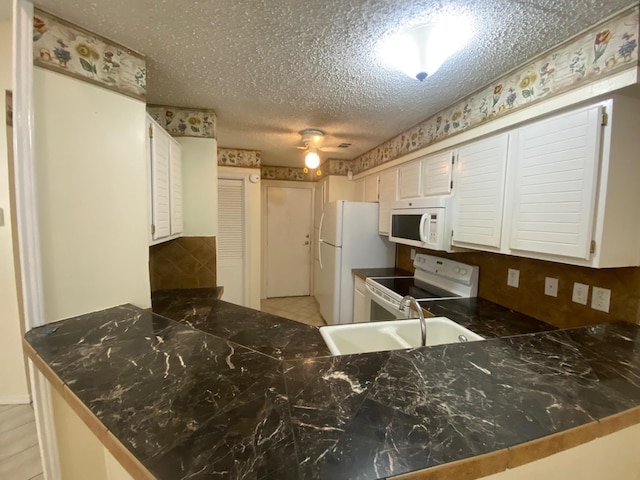 kitchen featuring white appliances, white cabinets, and kitchen peninsula