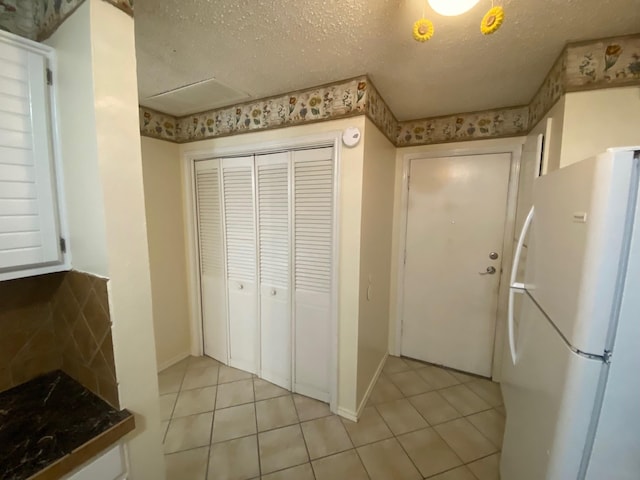 kitchen featuring a textured ceiling, light tile patterned floors, and white fridge