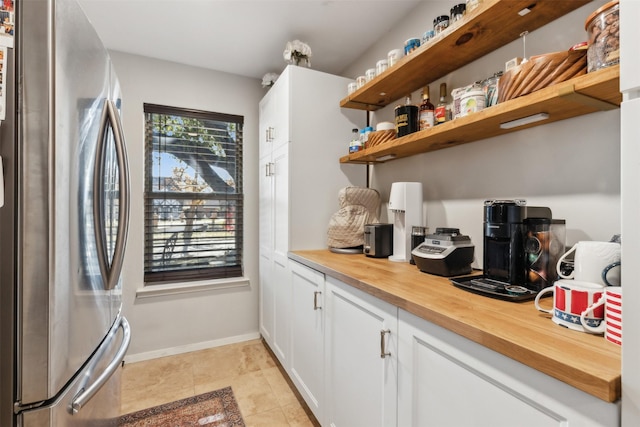 interior space featuring white cabinets, stainless steel fridge, and wooden counters