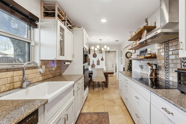 kitchen with wall chimney exhaust hood, white cabinetry, black electric stovetop, decorative backsplash, and wall oven