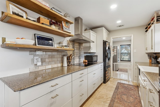 kitchen with white cabinets, island exhaust hood, dark stone countertops, black appliances, and decorative backsplash