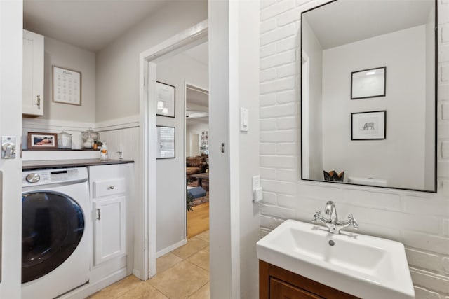 laundry area featuring cabinets, sink, light tile patterned floors, and washer / dryer