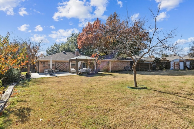 view of front of property with a patio area, a gazebo, a front yard, and a storage unit