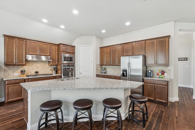 kitchen featuring stainless steel appliances, a center island with sink, and a kitchen breakfast bar