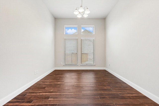 spare room with dark hardwood / wood-style flooring and a notable chandelier