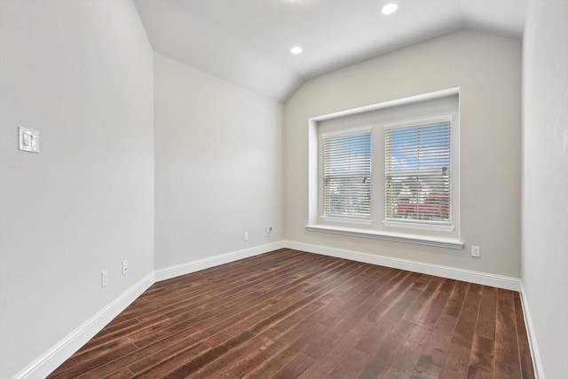 spare room featuring dark wood-type flooring and lofted ceiling