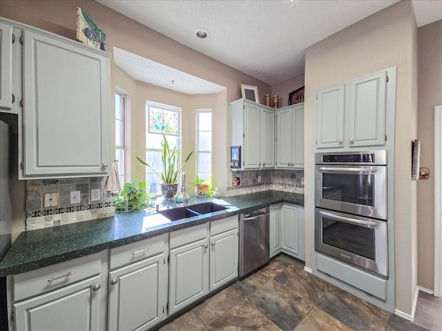 kitchen with sink, backsplash, white cabinets, and appliances with stainless steel finishes