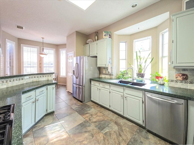 kitchen with a textured ceiling, tasteful backsplash, sink, pendant lighting, and stainless steel appliances