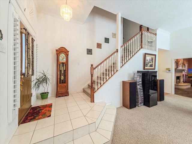 entryway with a high ceiling, crown molding, light carpet, and an inviting chandelier