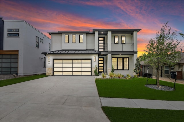 contemporary house featuring a garage, a lawn, and a balcony