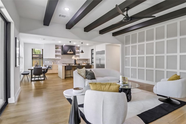 living room featuring ceiling fan, beamed ceiling, and light hardwood / wood-style flooring