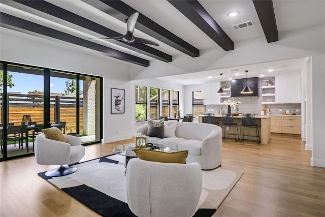 living room featuring light wood-type flooring, ceiling fan, and beamed ceiling