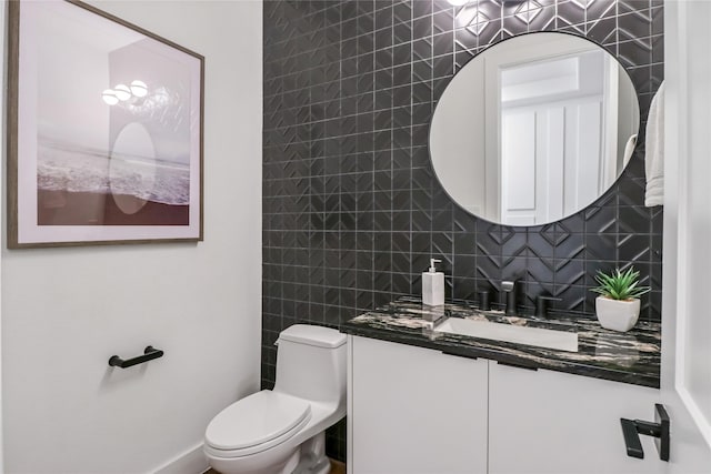 bathroom featuring vanity, toilet, and backsplash