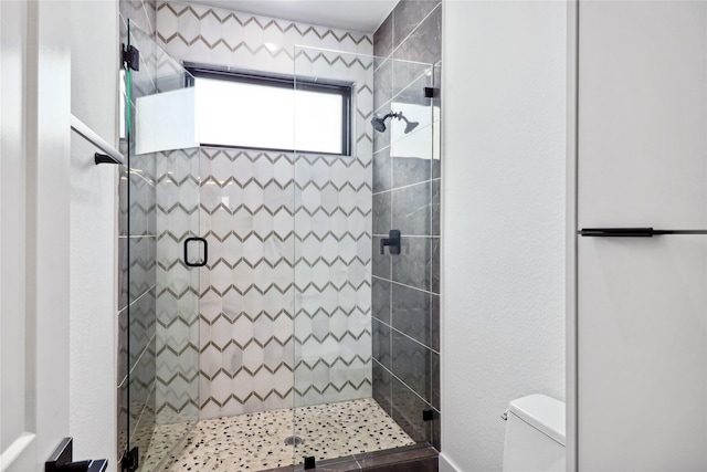 bathroom featuring toilet and a shower with shower door