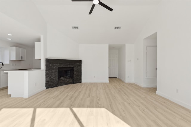 unfurnished living room featuring ceiling fan, sink, light wood-type flooring, and vaulted ceiling