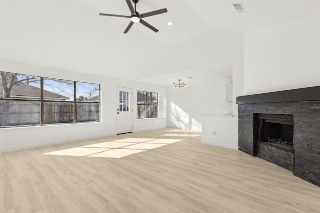 unfurnished living room featuring light wood-type flooring, ceiling fan with notable chandelier, vaulted ceiling, and a stone fireplace