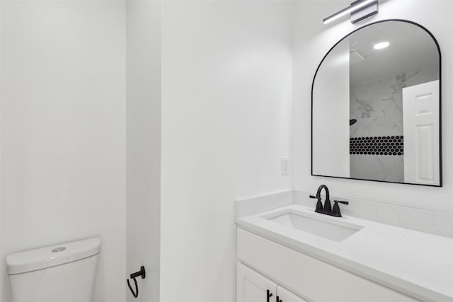 bathroom featuring toilet, vanity, and tiled shower