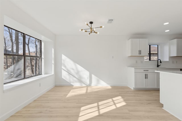 kitchen featuring white cabinets, light hardwood / wood-style floors, plenty of natural light, and sink