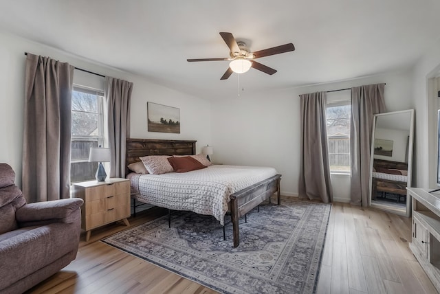 bedroom with ceiling fan, light hardwood / wood-style floors, and multiple windows