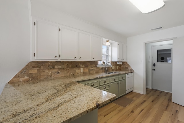 kitchen with white dishwasher, sink, white cabinets, green cabinetry, and decorative backsplash