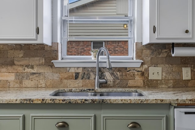 room details with dishwasher, sink, backsplash, light stone countertops, and green cabinetry