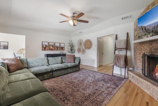 living room with ceiling fan, light hardwood / wood-style flooring, a fireplace, and lofted ceiling