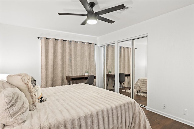 bedroom with ceiling fan, dark wood-type flooring, visible vents, baseboards, and multiple closets