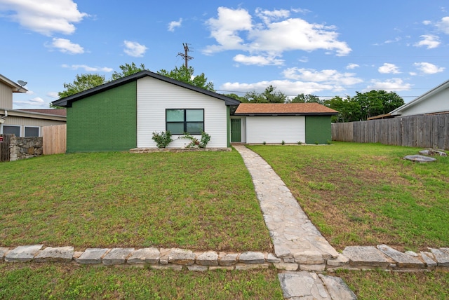 mid-century modern home with brick siding, a front yard, and fence