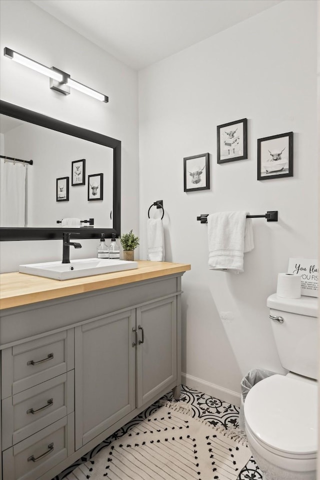 bathroom with baseboards, toilet, and vanity