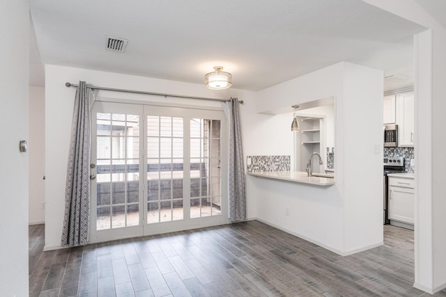 interior space featuring tasteful backsplash, white cabinetry, dark hardwood / wood-style flooring, and appliances with stainless steel finishes