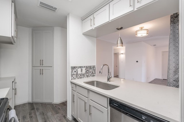 kitchen with stainless steel dishwasher, dark hardwood / wood-style flooring, sink, decorative light fixtures, and white cabinets