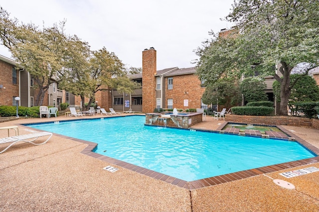 view of swimming pool featuring pool water feature, a community hot tub, and a patio area